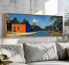 a painting hanging on the wall above a couch in a room with a white sofa