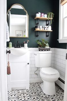 a white toilet sitting under a bathroom mirror next to a wall mounted shelf filled with bottles