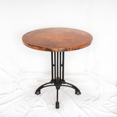 a round wooden table sitting on top of a white sheet