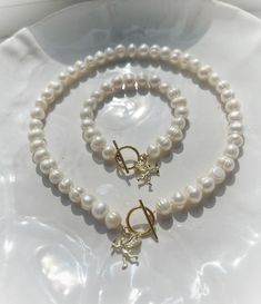 This white pearl charm necklace and bracelet matching set with a dainty gold Cupid / cherub charm combines classic white pearl jewelry with golden charm details to create unique pieces of pearl jewelry. Genuine white 10mm freshwater pearls sit alongside a gold plated brass toggle clasp for easy wearing, finished with a beautiful dainty gold plated cherub charm.  The ideal pieces of jewelry for Summer! Cupid Cherub, Bracelet Matching, White Pearl Jewelry, Pearl Charm Necklace, Pearl Accessories, Freshwater Pearl Jewelry, White Pearl Necklace, Jewelry Pearl, Gift Inspiration