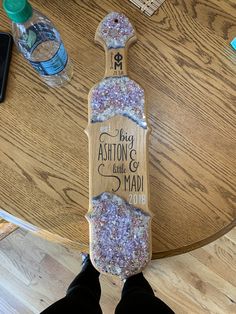 a skateboard with glitter on it sitting on top of a table next to a person's feet