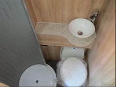 a small bathroom with a toilet, sink and wooden paneling on the wall behind it