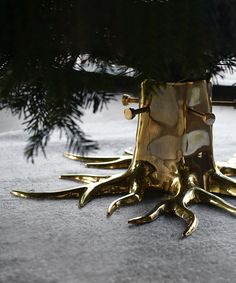 a gold vase sitting on top of a floor next to a tree