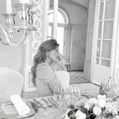 a woman sitting at a table in front of a mirror with wine glasses on it