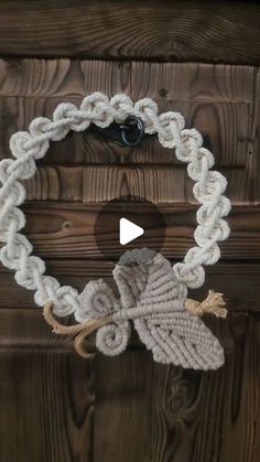 a white rope bracelet on top of a wooden door with an owl charm hanging from it's side