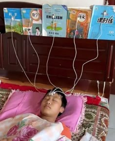 a young boy laying in bed with headphones attached to the wires above his head