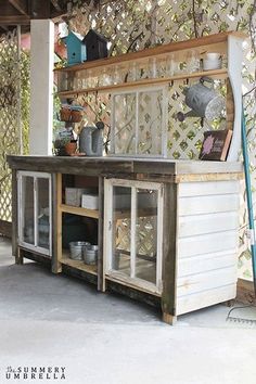 an outdoor kitchen with pots and pans on the outside wall, under a pergolated roof