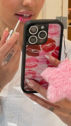 a woman is holding a cell phone case with food on it and lipstick in her mouth