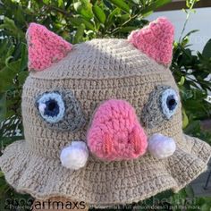 a crocheted animal hat with big eyes and ears is hanging from a tree