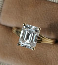 an engagement ring with a large emerald cut diamond on it's shanty band