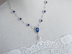 Blue Sapphire Necklace, Bridal Pearl/Sapphire CZ Necklace, Something Blue Necklace, Wedding Jewelry, Bridal Jewelry, Sapphire Pearl Necklace Materials: - 9mm rhodium plated blue sapphire and white cubic zirconia connectors  - rhodium plated over brass chain - white/Ivory Cream Swarovski pearls - 15x24mm Blue Sapphire cubic zirconia teardrop pendant The listing is for one necklace.  ❤❤ ❤BRIDAL and BULK ORDERS DISCOUNT ❤ ❤❤  5% Discount : 2 items (Use Coupon Code - 5DISCOFF) 10% Discount : 3-5 items (Use Coupon Code - 10DISCOFF) 15% Discount : 6 items and more (Use Coupon Code - 15DISCOFF) Here is a helpful link how to use the coupon code discount: www.etsy.com/help/article/350 The necklace will arrive packaged ready for gift giving in a delicate white jewelry box with a silver ribbon. Match Sapphire Necklace Simple, Sapphire Necklace Wedding, Royal Blue Jewelry, Unique Wedding Jewelry, Blue Wedding Jewelry, Jewelry Sapphire, Blue Sapphire Necklace, Bridal Pearl Necklace, Pearl Necklace Vintage