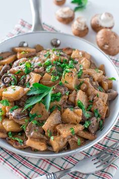 a white bowl filled with pasta and mushrooms on top of a checkered table cloth