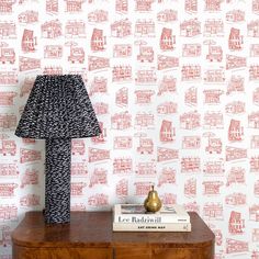 a lamp sitting on top of a wooden dresser next to a wallpapered wall