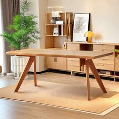 a wooden table sitting on top of a hard wood floor next to a plant in a living room