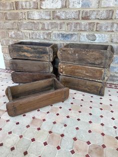 three wooden boxes sitting on top of a tiled floor next to a brick wall and door