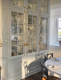 a china cabinet with glass doors and plates on the front, in a dining room