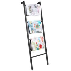 a black metal magazine rack with magazines on the top and bottom shelves, against a white background