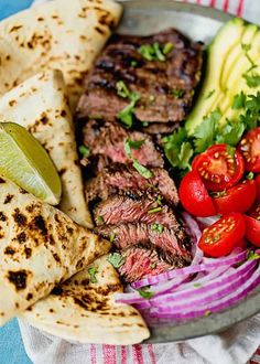 a plate filled with meat, vegetables and pita bread