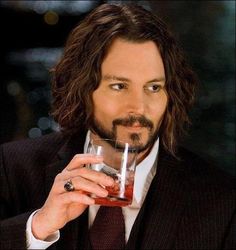 a man with long hair holding a glass in his hand