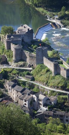 an aerial view of a river running through a city with old buildings and trees around it