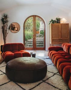 a living room filled with red couches and a round ottoman on top of a rug