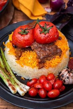 a black plate topped with rice and tomatoes