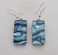 the earrings are made from glass and have silver earwires on them, with blue designs