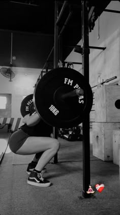 a woman squats on the ground while holding a barbell