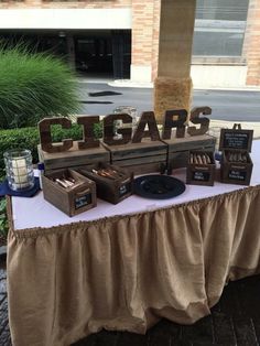 a table that has some items on it and is set up for an event with the word cigars written in large letters