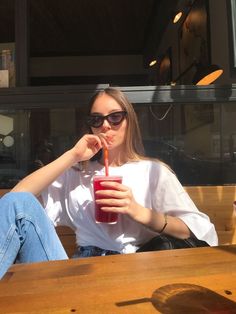 a woman sitting at a table with a drink in her hand