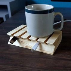 a coffee cup sitting on top of a wooden coaster with a charger attached to it