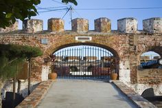 an old brick gate with iron bars on the top and bottom, leading to a parking lot