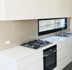 a kitchen with a stove top oven next to a sink and countertop under a flat screen tv