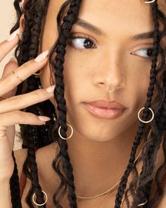 a close up of a person with dreadlocks on her head and wearing gold rings