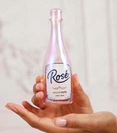 a hand holding a bottle of rose wine