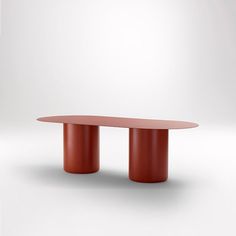 an oval table with two red bases in front of a white wall and grey background