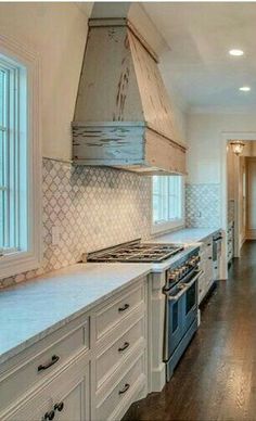 a kitchen with white cabinets and an oven in the middle of it, along with hardwood flooring