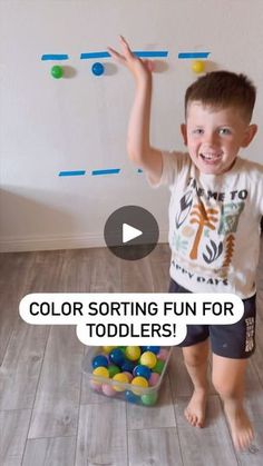 a young boy standing in front of a bucket filled with balls and playing with his toys