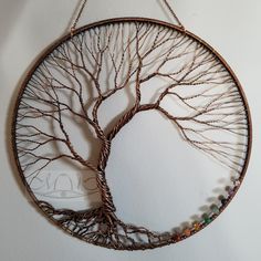 a circular metal wall hanging with a tree on it's side and beads around the branches