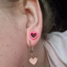 a close up of a person's ear with a heart shaped earring on it