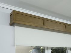 an open window with white roller shades and wood trim on the bottom half of it