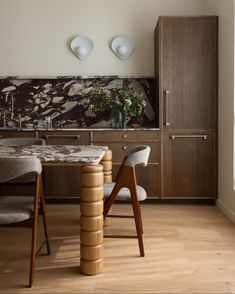 a dining room table and chairs in front of a wall with marbled backsplash