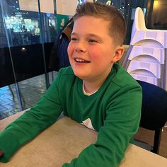 a young boy sitting at a table with a doughnut in front of him