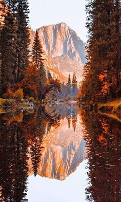 the mountains are reflected in the still water on the lake's surface, with trees lining both sides