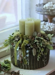 a basket filled with candles sitting on top of a window sill next to pine cones