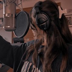 a woman wearing headphones is recording in front of a microphone