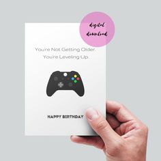 someone holding up a card with a video game controller on it that reads, you're not getting older, you're leveling up happy birthday