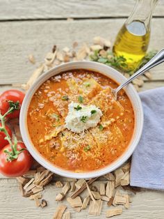 a bowl of soup with tomatoes, parmesan cheese and herbs on the side