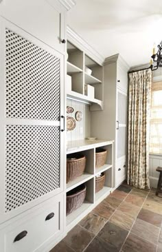 a room with white cabinets and baskets on the shelves