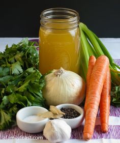 carrots, onions, celery, and other vegetables are on a table